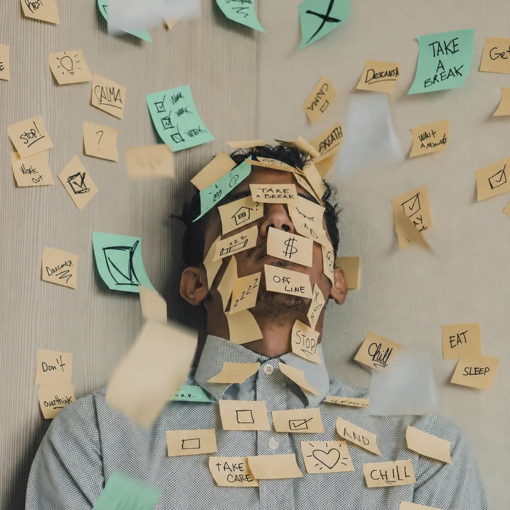 A person with sticky notes covering their face and shirt, surrounded by more notes on a wall.